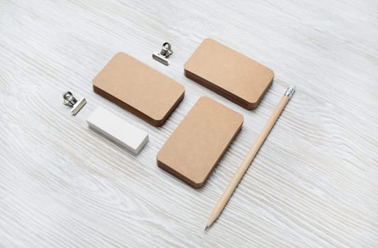 Branding mock up. Blank vintage business cards, pencil and eraser on light wood table background.