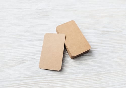 Photo of blank kraft business cards on light wooden background. Template for ID.