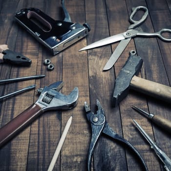 Old used work tools on vintage wooden background.