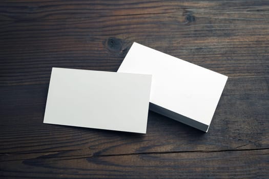 Blank white business cards on wooden background. Mockup for branding identity. Template for graphic designers portfolios.