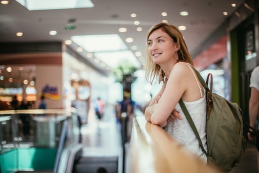 Young girl is leaning on the handrail in a shopping mall, blurry background
