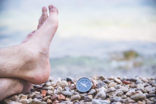 Compass and mans feet on beach, enjoy and text space