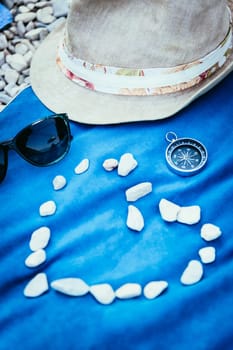 Summer holiday vacation accessories on beach, heart out of stones