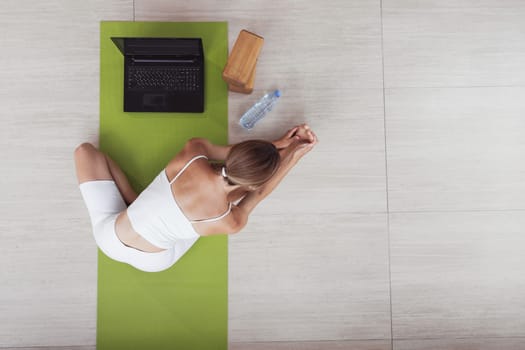 Attractive sportswoman doing workout online with laptop. Top view