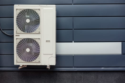 Air compressor installation on metal tiled wall of modern building.