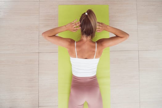 Woman doing back extension exercise on fit ball with online trainer. Top view