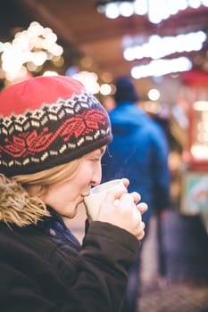 Girl is drinking mulled wine on the Christmas market, fun