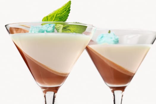 Panna cotta is a traditional Italian cream dessert in a white and brown glass, garnished with a blue molecular biscuit