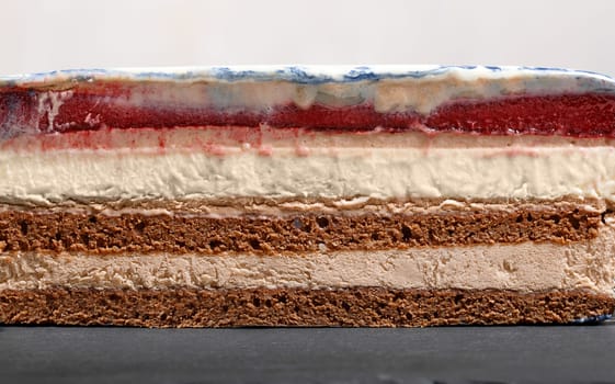 Cross-section mousse cake with berry, biscuit mousse and cream layers