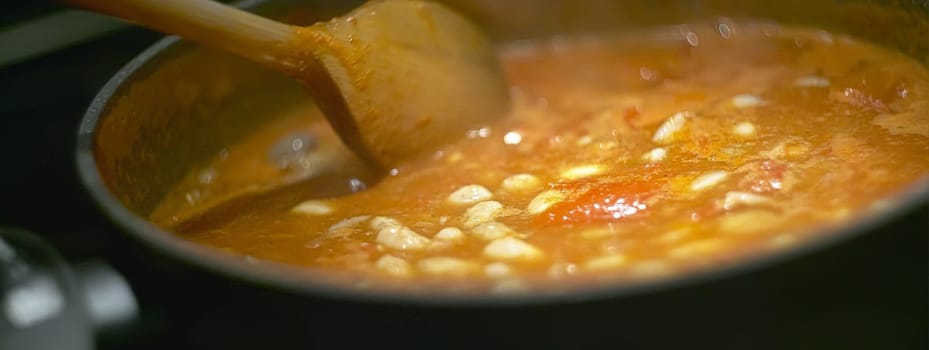 Pot of gravy or soup while cooking on the stove and is stirred to achieve the perfect cooking to be served.