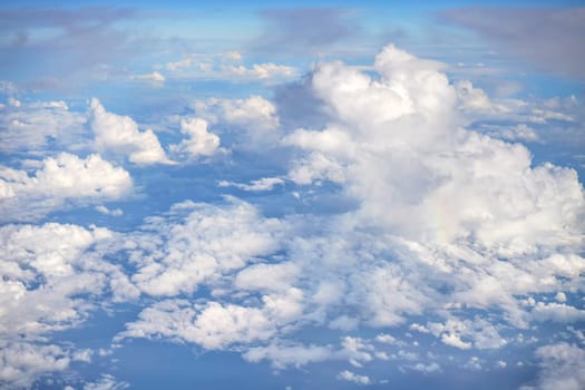 Fluffy sky clouds lit by afternoon sun, as seen from commercial airplane flying over.