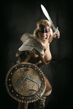 Ancient woman warrior or Gladiator posing with sword and shield, isolated in a dark background