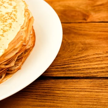 Pancakes on a plate on a wooden table. A large stack of fresh pancakes. Delicious healthy fresh pancakes. Place for advertising, logo, lettering, layout, mockup.