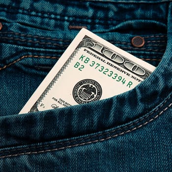 A hundred-dollar bill in the pocket of his jeans. The one hundred American dollar bill is sticking out. One bill is US dollars. Color style.