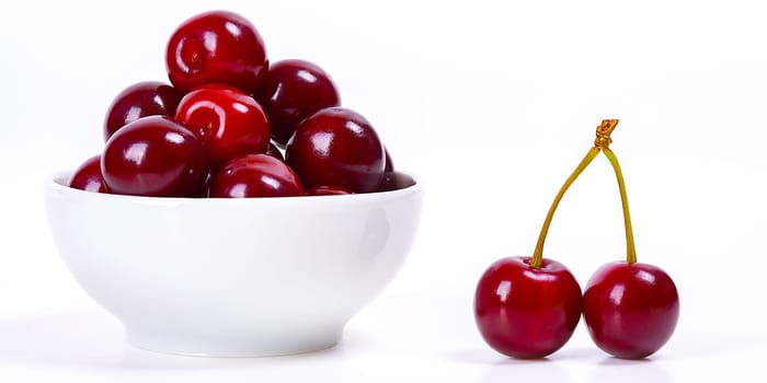 Cherry berries in a white cup on a white background. Isolated. Ripe cherries. Red delicious cherry. Place for advertising, lettering, logo, text, layout, mockup.