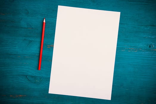 A blank white sheet and pencil for drawing on a wooden background with space for copying and lettering. Layout, mockup free space.