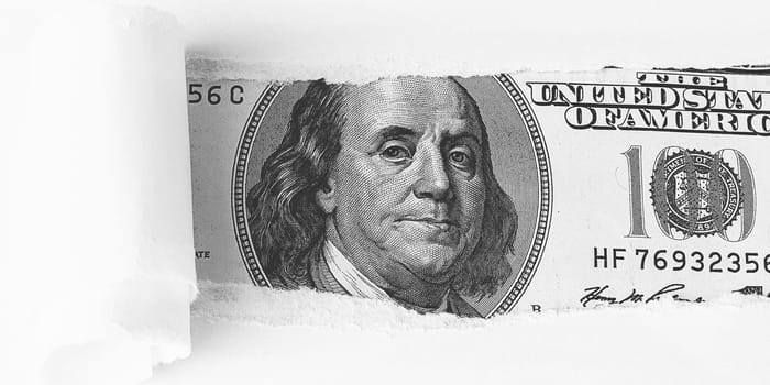 The face of Benjamin Franklin on a hundred-dollar bill, from a torn window in white paper. Background, white. Isolated. Close-up. A hundred-dollar American bill with the eyes of Benjamin Franklin. Black and white style. Place for logo, lettering, sign, template, mockup.