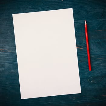 A blank white sheet and pencil for drawing on a wooden background with space for copying and lettering. Layout, mockup free space.