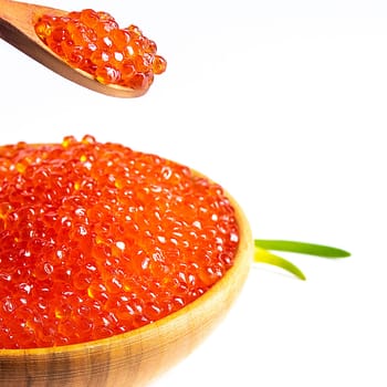Red caviar in a wooden cup on a white background with a spoon and green onions. A large pile of bright caviar. Fresh delicious caviar. Isolated. A place for advertising, logo, label, layout, mockup. Layout, template.