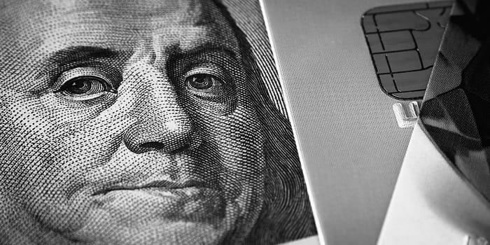 Benjamin Franklin's face on a hundred-dollar bill next to a credit card. Close-up. A hundred-dollar American bill with the eyes of Benjamin Franklin. Black and white style. Layout, template, layout.