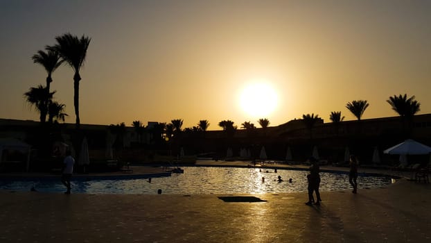 pool at night in one of the hotels near the beach. Sunset over the pool at the hotel. Infinity pool at dusk. Silhouette moment over beach side.