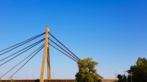 Ukraine, Kiev - August 20, 2019: A bridge across the river with pulling ropes. North bridge against the backdrop of a beautiful simple blue sky without clouds in Kiev. R. Dnieper. Ukraine. Scenery
