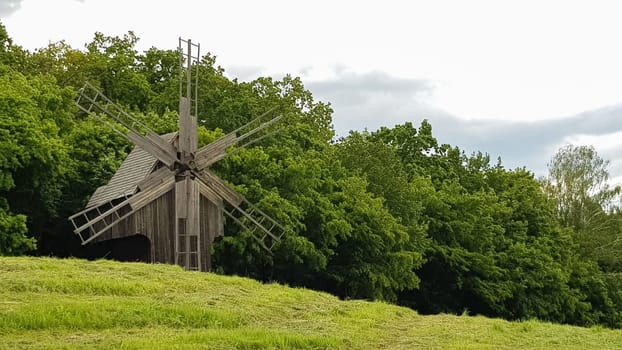 Ukraine, Kiev - June 11, 2020. Old Ukrainian wooden windmills of the XIX century. Summer outdoor landscape. Open-air museum of folk architecture and life, Pirogovo, Ukraine. Tourism and travel