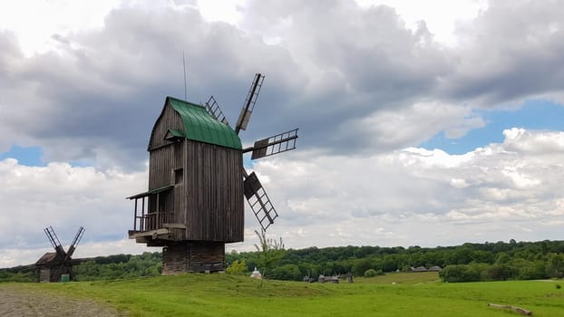 Ukraine, Kiev - June 11, 2020. Old Ukrainian wooden windmills of the XIX century. Summer outdoor landscape. Open-air museum of folk architecture and life, Pirogovo, Ukraine. Tourism and travel
