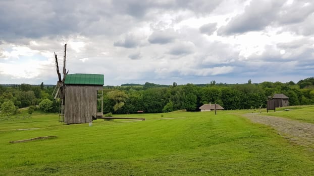 Ukraine, Kiev - June 11, 2020. Old Ukrainian wooden windmills of the XIX century. Summer outdoor landscape. Open-air museum of folk architecture and life, Pirogovo, Ukraine. Tourism and travel