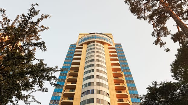 Ukraine, Kiev - May 25, 2020: modern multi-storey residential building against the blue sky and green trees. Exterior wall of a colorful residential new building. View from below