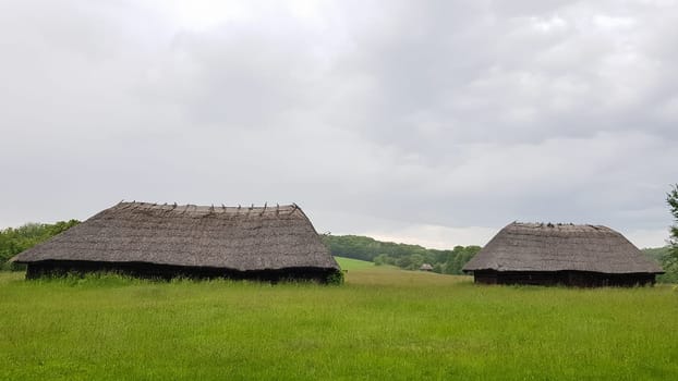 Ukraine, Kiev - June 11, 2020. Old peasant Ukrainian house or barn in the summer with a thatched roof in the village. Pirogovo Museum in the open air of different regions of Ukraine
