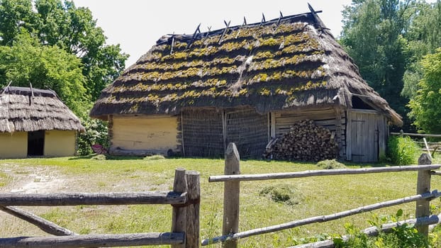 Ukraine, Kiev - June 11, 2020. Old peasant Ukrainian house or barn in the summer with a thatched roof in the village. Pirogovo Museum in the open air of different regions of Ukraine