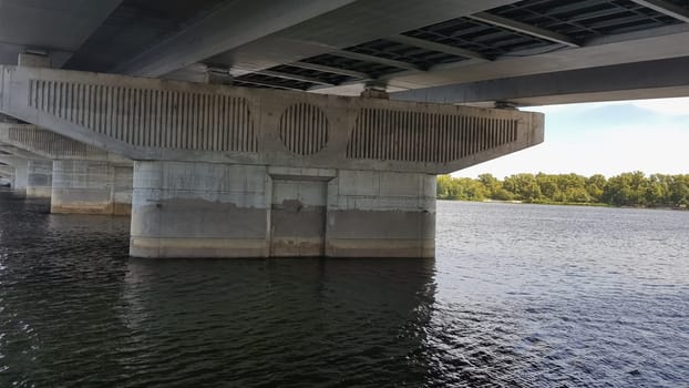 Close-up concrete support of an iron bridge in a river