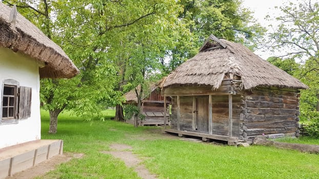 Ukraine, Kiev - June 11, 2020. Old peasant Ukrainian house or barn in the summer with a thatched roof in the village. Pirogovo Museum in the open air of different regions of Ukraine