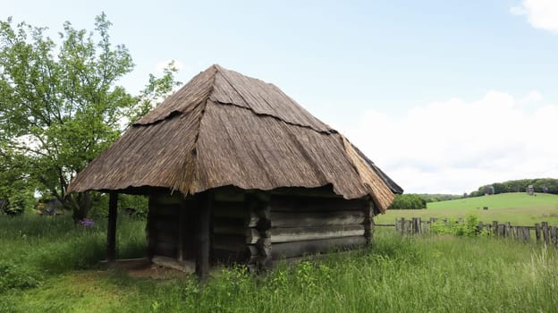 Ukraine, Kiev - June 11, 2020. Old peasant Ukrainian house or barn in the summer with a thatched roof in the village. Pirogovo Museum in the open air of different regions of Ukraine