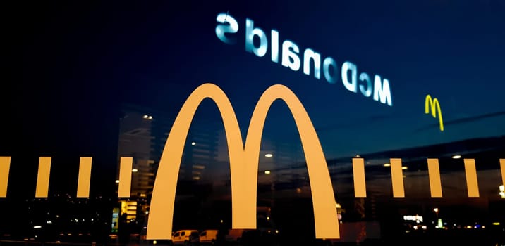 Ukraine, Kiev - August 23, 2019: view from the veranda of the McDonalds restaurant. Glass with a logo near the road at night.