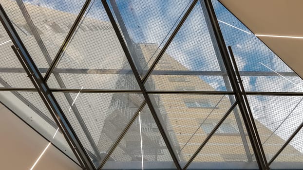 Ukraine, Kiev - September 24, 2019: Structural glazing of the facade. Abstract background with glass ceiling elements in a modern building. view of the blue sky through a glass window, separated by lattice elements