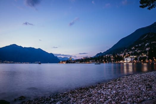 Beautiful evening scenery on the beach with cute little village, lago di garda, Italy.