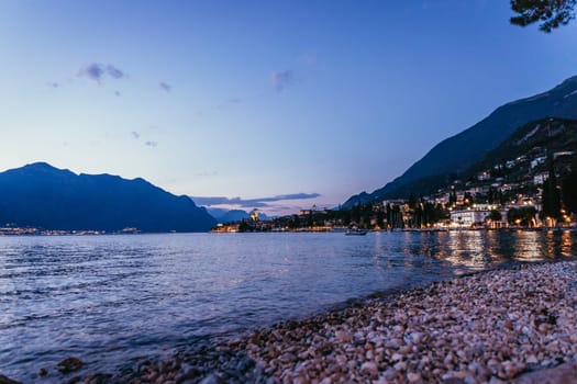 Beautiful evening scenery on the beach with cute little village, lago di garda, Italy.