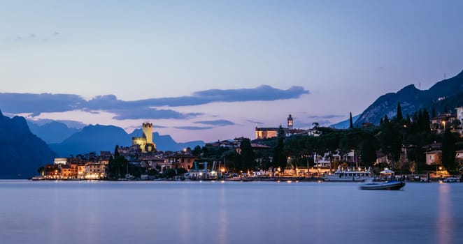 Beautiful evening scenery on the beach with cute little village, lago di garda, Italy.