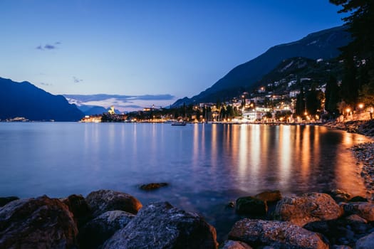Beautiful night  scenery with cute little village, lago di garda, Italy. Stones in the foreground.