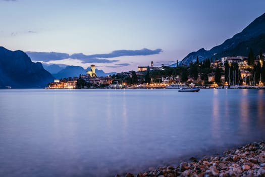 Beautiful evening scenery on the beach with cute little village, lago di garda, Italy.