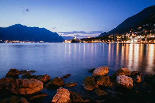 Beautiful night  scenery with cute little village, lago di garda, Italy. Stones in the foreground.