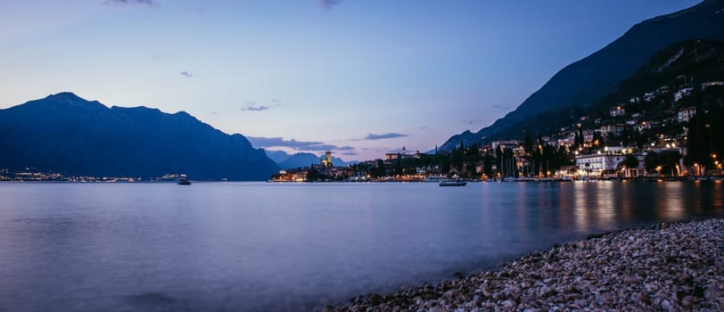 Beautiful evening scenery on the beach with cute little village, lago di garda, Italy.