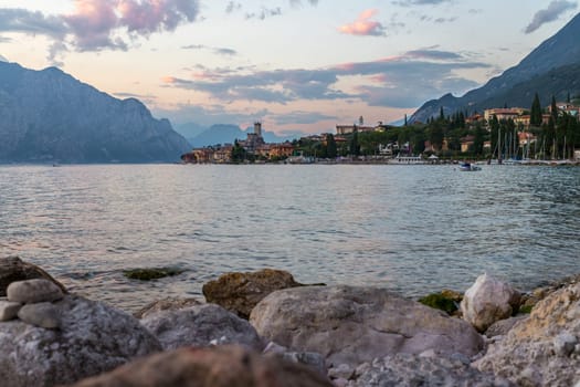 Beautiful evening scenery with cute little village, lago di garda, Italy. Stones in the foreground.
