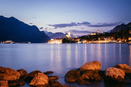 Beautiful night  scenery with cute little village, lago di garda, Italy. Stones in the foreground.