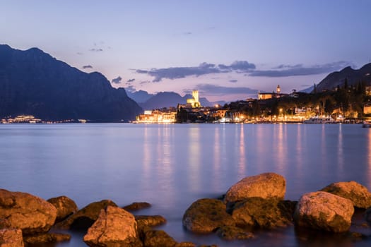Beautiful night  scenery with cute little village, lago di garda, Italy. Stones in the foreground.