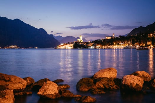 Beautiful night  scenery with cute little village, lago di garda, Italy. Stones in the foreground.