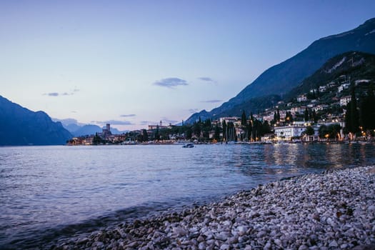 Beautiful evening scenery on the beach with cute little village, lago di garda, Italy.