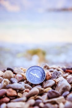 Compass on the beach, small stones, text space